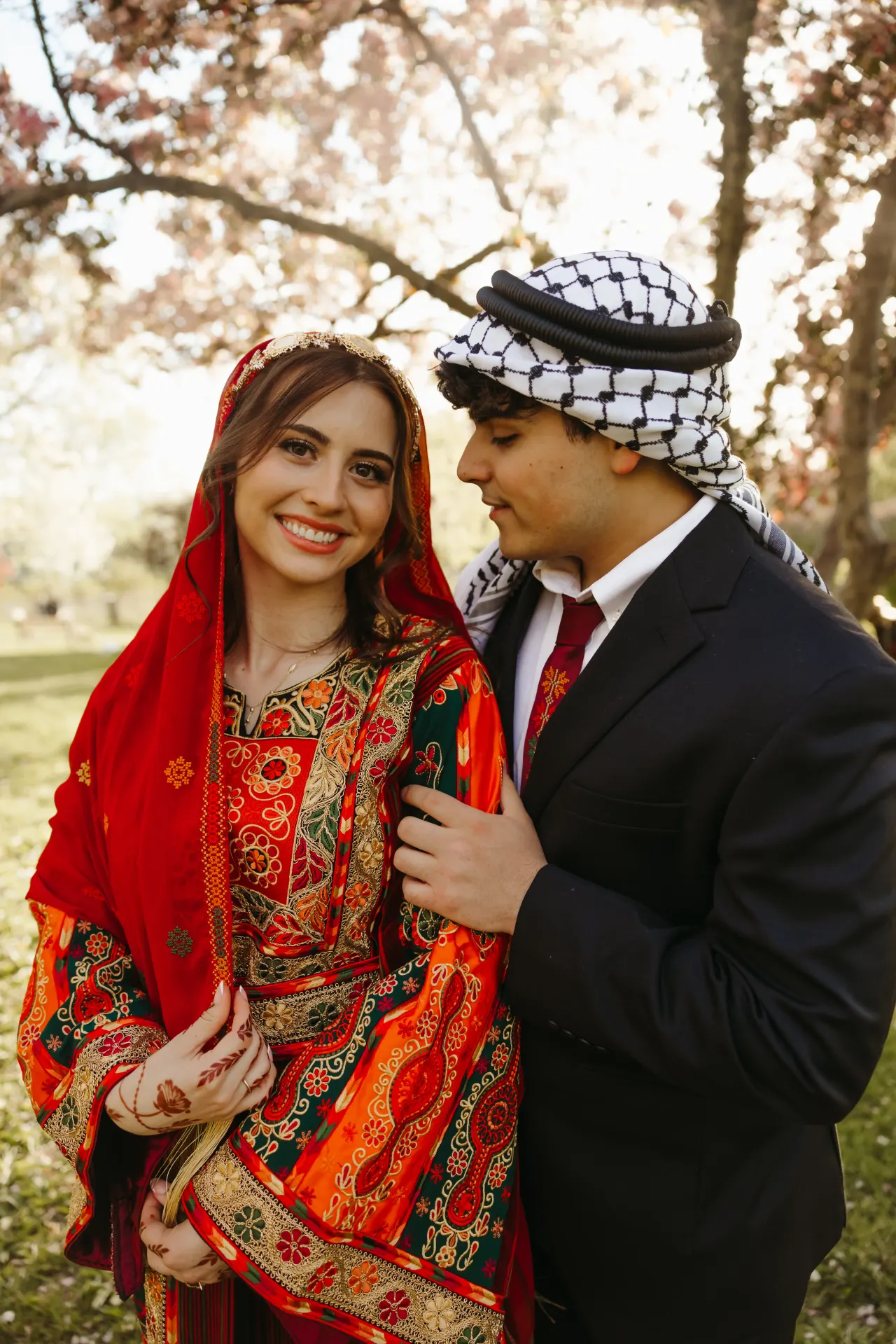 Bride in a red embroidered thobe with henna and groom in a keffiyeh beneath autumn trees — Minneapolis & Twin Cities wedding photography by Emma Ziegler, Honey Deww Photography (Minnesota)