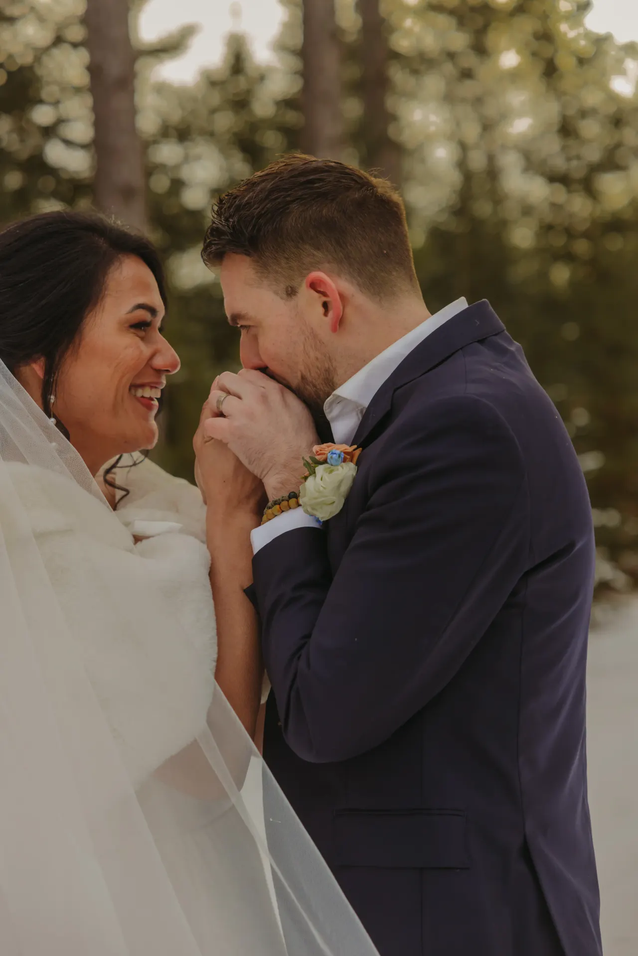 Groom kissing his bride's hand in the snow as she laughs — Minneapolis & Twin Cities wedding photography by Emma Ziegler, Honey Deww Photography (Minnesota)