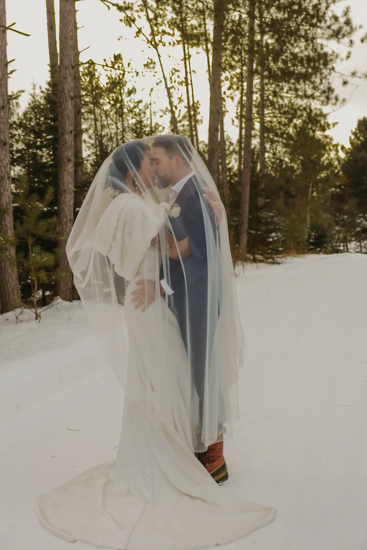 Bride and groom kissing beneath her veil on a snow-covered path — Minneapolis & Twin Cities wedding photography by Emma Ziegler, Honey Deww Photography (Minnesota)