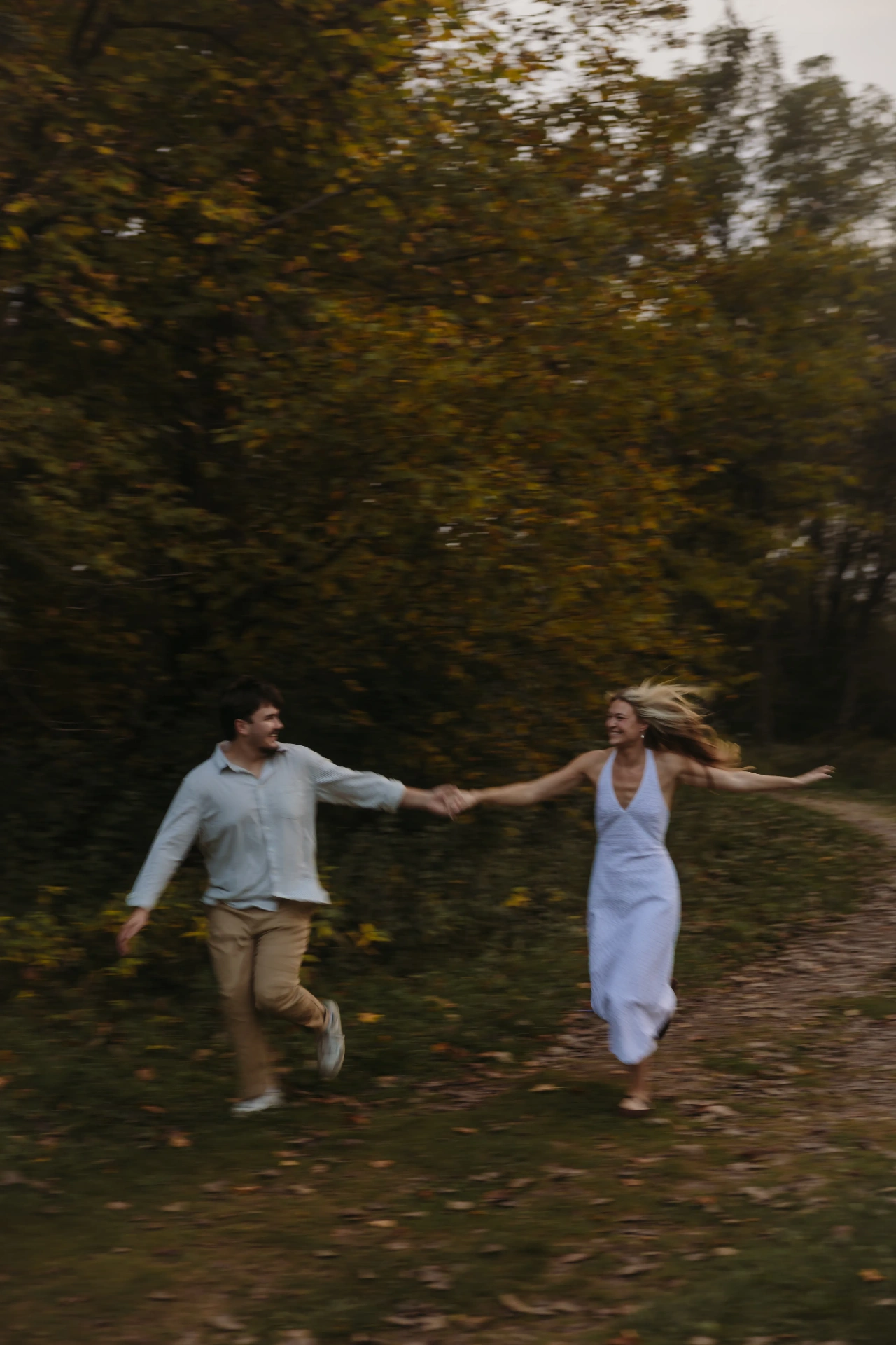 Couple running hand in hand through autumn foliage