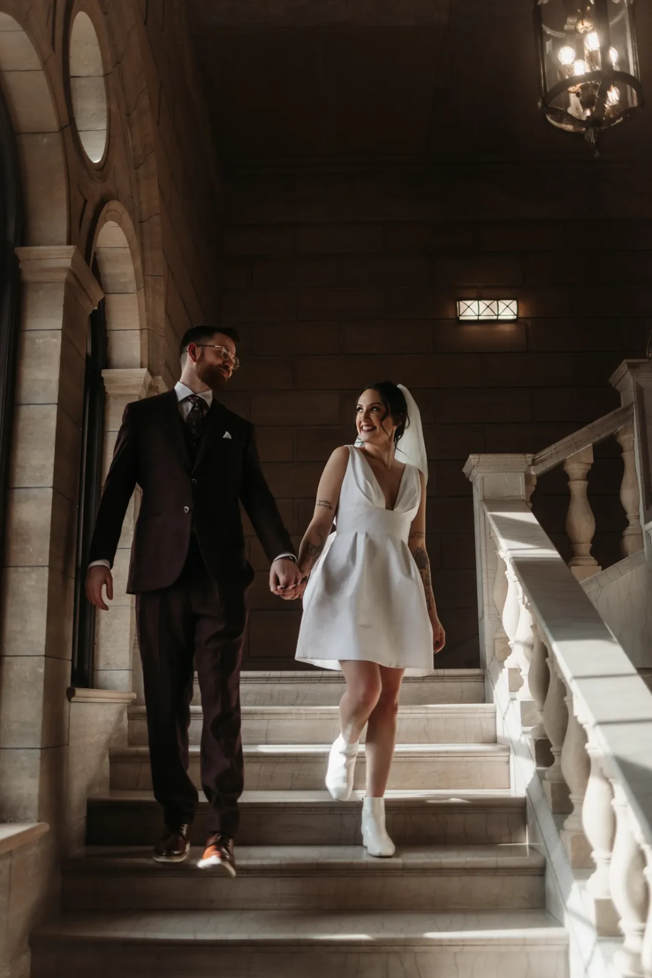 Couple walking down ornate stone staircase hand in hand