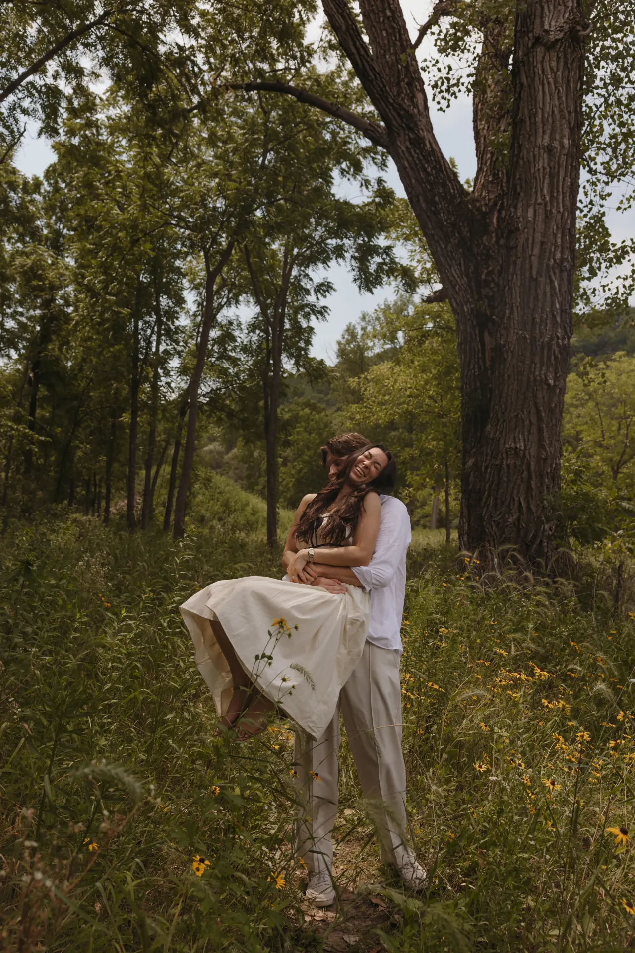 Groom carrying his laughing bride beneath a wide cottonwood tree — Minneapolis & Twin Cities wedding photography by Emma Ziegler, Honey Deww Photography (Minnesota)