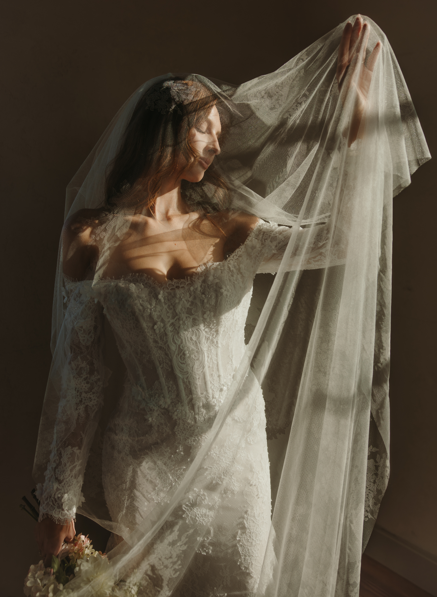 Bride lifting veil in dramatic light