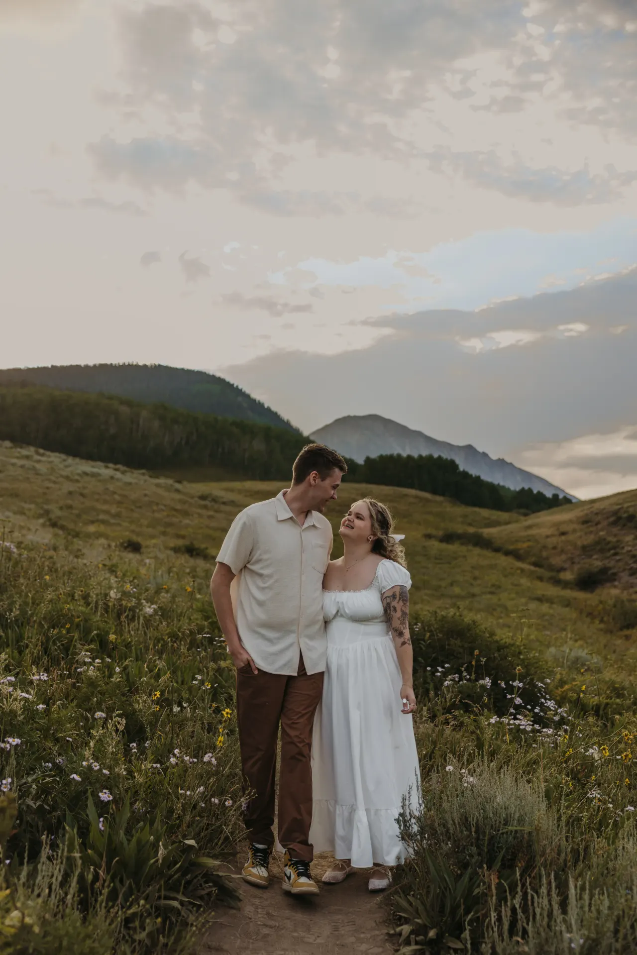 Couple walking a mountain meadow path at sunset with peaks behind them — Minneapolis & Twin Cities wedding photography by Emma Ziegler, Honey Deww Photography (Minnesota)