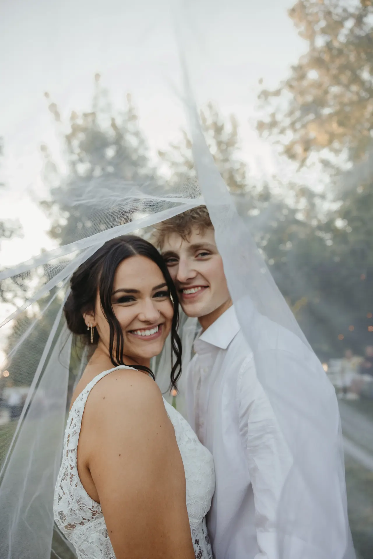 Bride and groom smiling out from beneath her veil at golden hour — Minneapolis & Twin Cities wedding photography by Emma Ziegler, Honey Deww Photography (Minnesota)