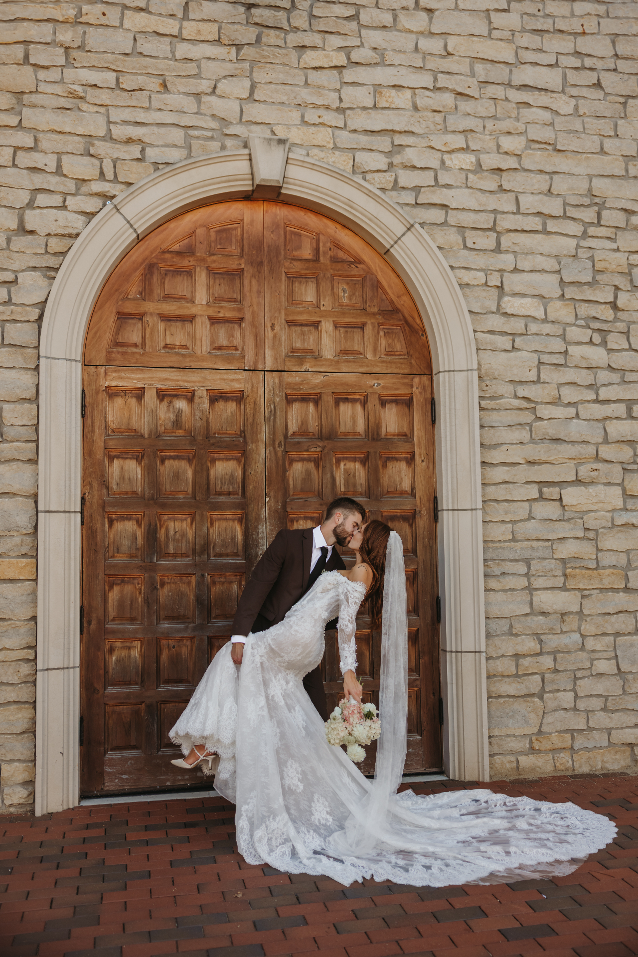 Couple kissing in front of stone church doors