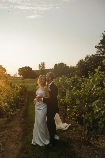 Groom kissing bride in vineyard rows at golden hour — Edina, Minnesota wedding photography by Emma Ziegler, Honey Deww Photography
