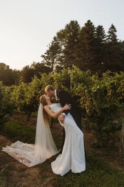 Groom dipping bride for kiss among grapevines at sunset — Red Wing, Minnesota wedding photography by Emma Ziegler, Honey Deww Photography
