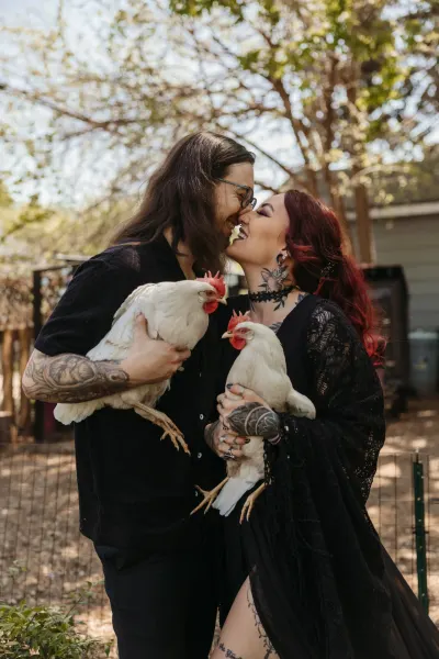 Tattooed couple in black holding white chickens and kissing — St. Paul, Minnesota wedding photography by Emma Ziegler, Honey Deww Photography