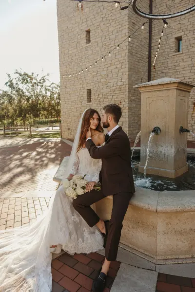 Bride and groom by stone fountain with string lights at venue — St. Paul, Minnesota wedding photography by Emma Ziegler, Honey Deww Photography
