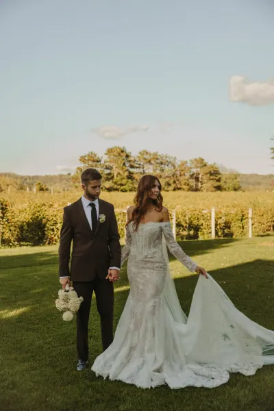 Bride and groom walking hand in hand past vineyard rows — Roberts, Minnesota wedding photography by Emma Ziegler, Honey Deww Photography