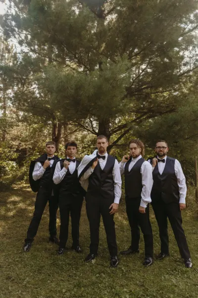 Groomsmen in vests and bow ties posing among pine trees — Roberts, Minnesota wedding photography by Emma Ziegler, Honey Deww Photography