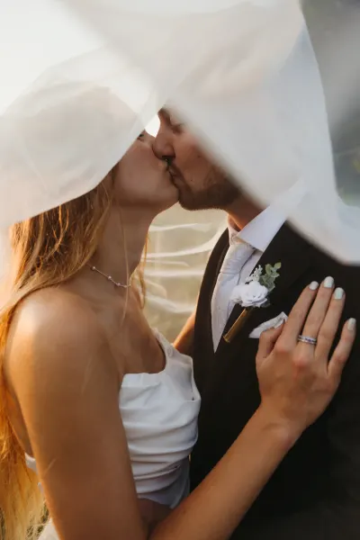 Bride and groom kissing under veil with boutonniere detail — St. Cloud, Minnesota wedding photography by Emma Ziegler, Honey Deww Photography