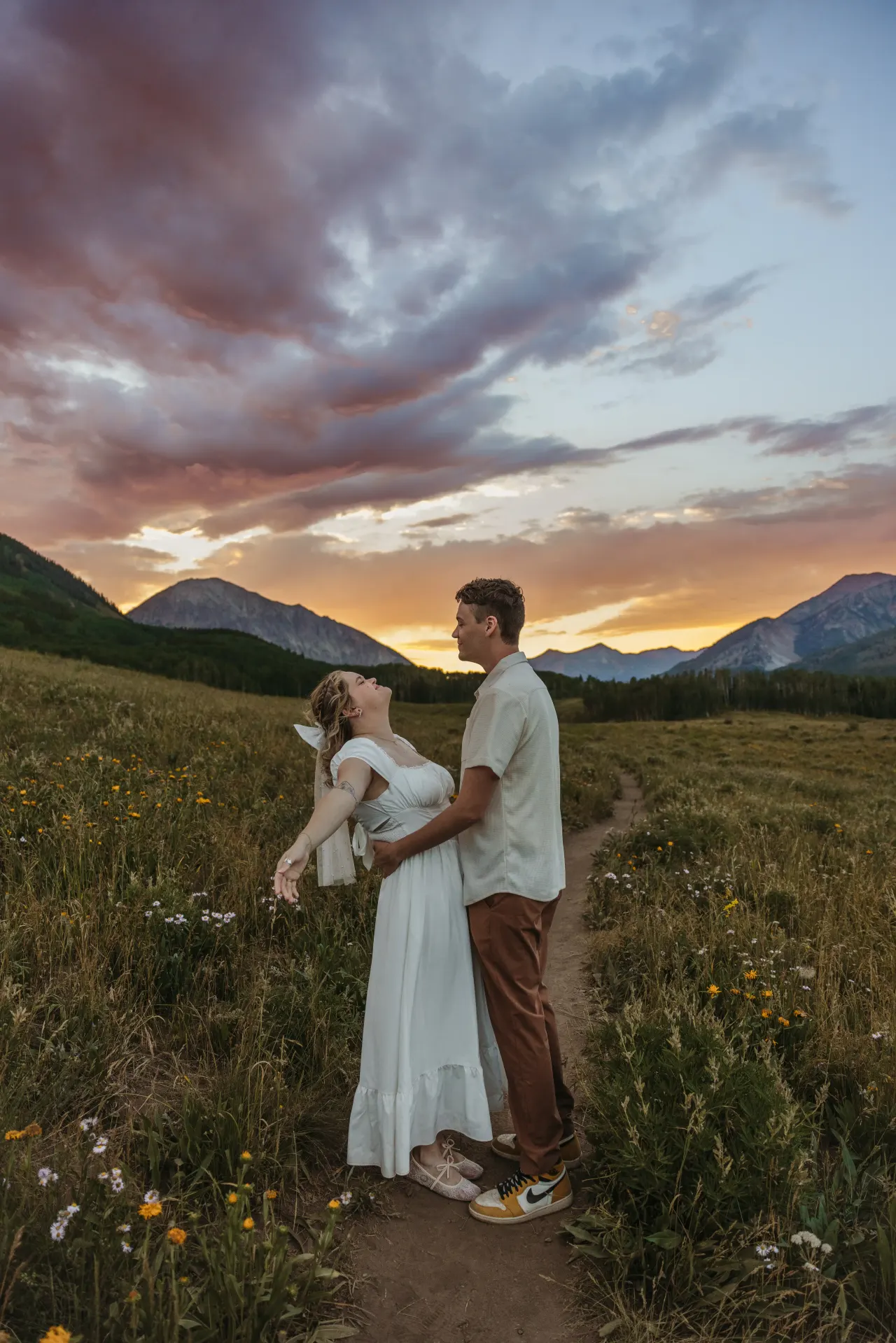 Bride leaning back laughing in her groom's arms as the sun sets over the peaks — Minneapolis & Twin Cities wedding photography by Emma Ziegler, Honey Deww Photography (Minnesota)