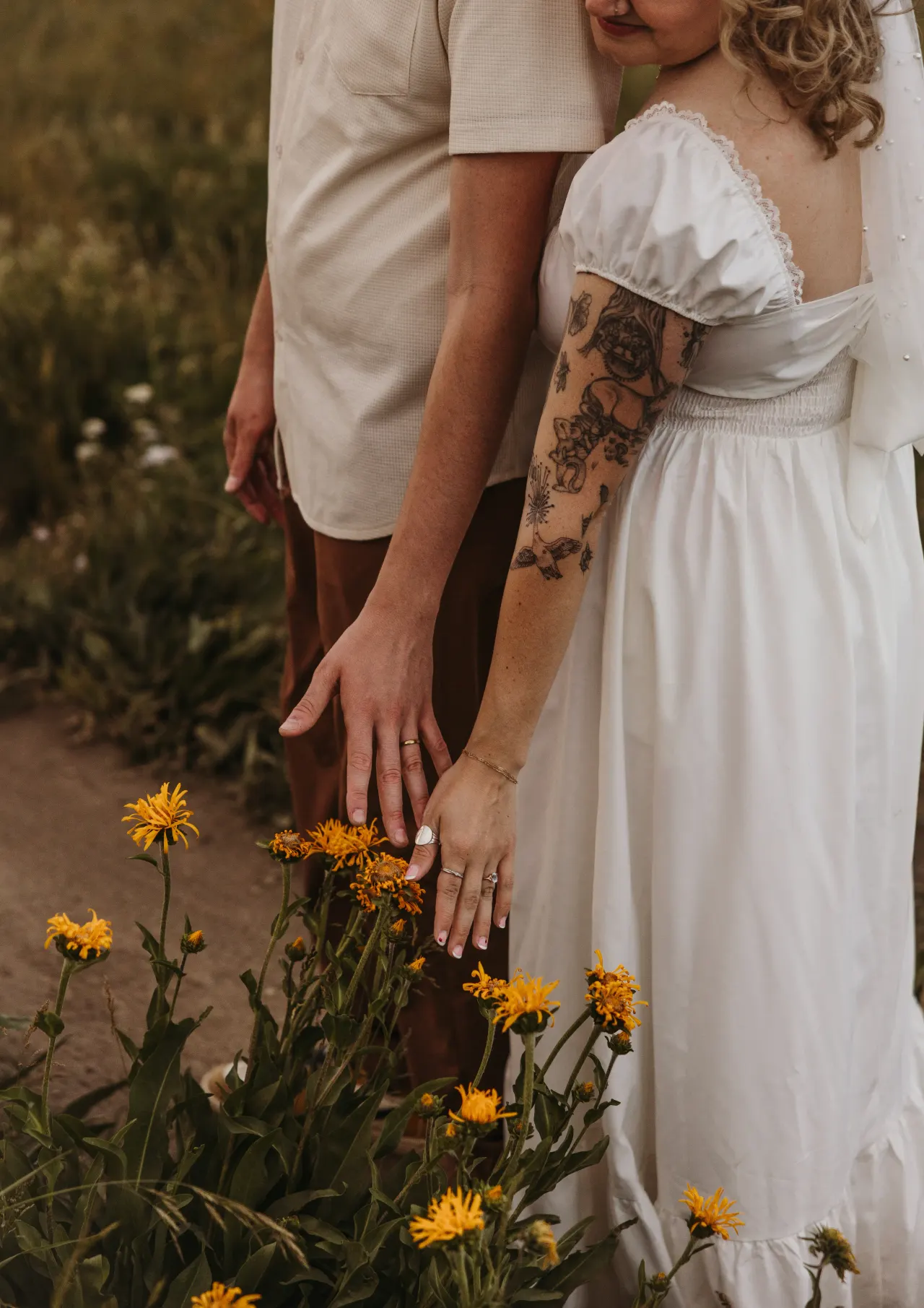Two hands wearing wedding rings held above yellow mountain wildflowers — Minneapolis & Twin Cities wedding photography by Emma Ziegler, Honey Deww Photography (Minnesota)