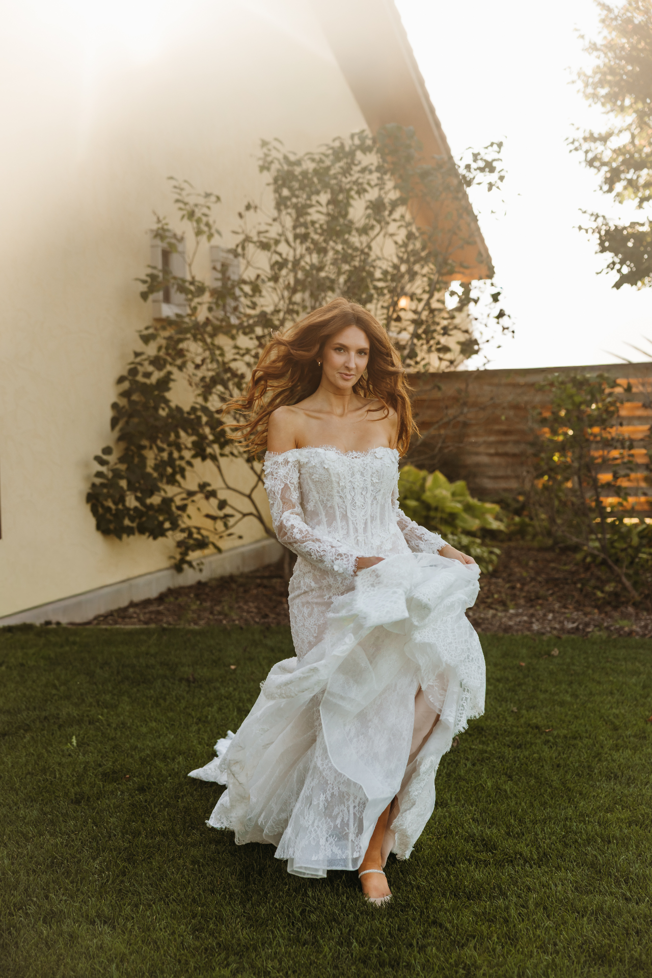 Bride in lace dress twirling in garden at golden hour