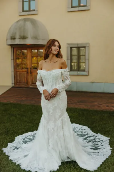 Bride in lace mermaid gown standing outside venue entrance — Woodville, Minnesota wedding photography by Emma Ziegler, Honey Deww Photography