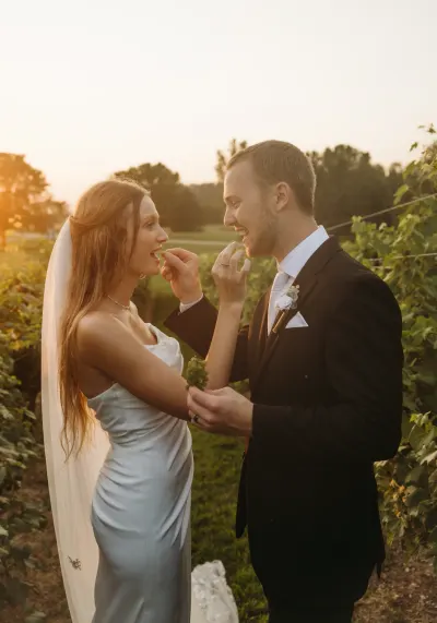 Couple feeding each other grapes in vineyard at sunset — Excelsior, Minnesota wedding photography by Emma Ziegler, Honey Deww Photography