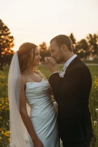 Groom kissing bride's hand in golden wildflower field at sunset — Excelsior, Minnesota wedding photography by Emma Ziegler, Honey Deww Photography