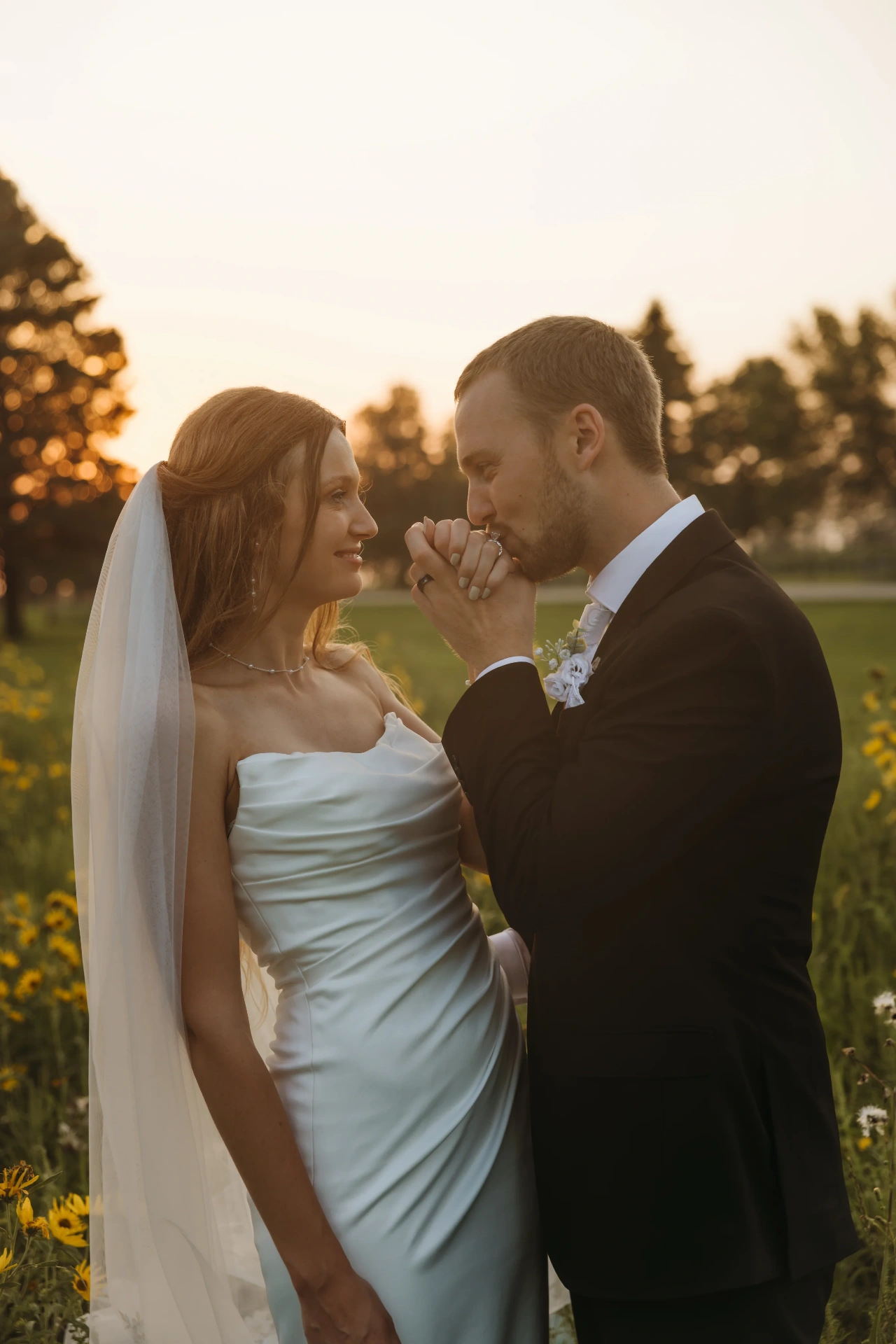 Groom kissing bride's hand in golden wildflower field at sunset — Minneapolis & Twin Cities wedding photography by Emma Ziegler, Honeydew Photography (Minnesota)
