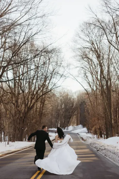 Bride and groom running down tree-lined winter road — Downing, Minnesota wedding photography by Emma Ziegler, Honey Deww Photography