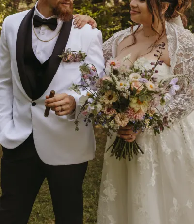 Groom with cigar in white jacket beside bride with wildflower bouquet — Downing, Minnesota wedding photography by Emma Ziegler, Honey Deww Photography