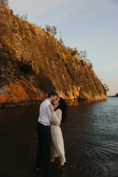 Couple kissing in water beside golden cliff at sunset — Downing, Minnesota wedding photography by Emma Ziegler, Honey Deww Photography