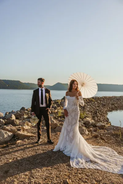 Bride with parasol and groom on rocky lakeshore with mountains — Aster Cafe, Minnesota wedding photography by Emma Ziegler, Honey Deww Photography