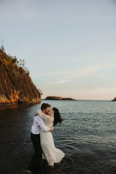 Couple kissing in water at golden hour with cliff backdrop — Aster Cafe, Minnesota wedding photography by Emma Ziegler, Honey Deww Photography