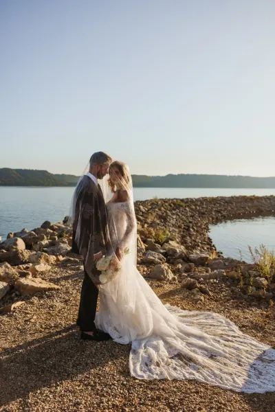 Bride and groom under veil on rocky lakeshore at sunset — Hammond, Minnesota wedding photography by Emma Ziegler, Honey Deww Photography