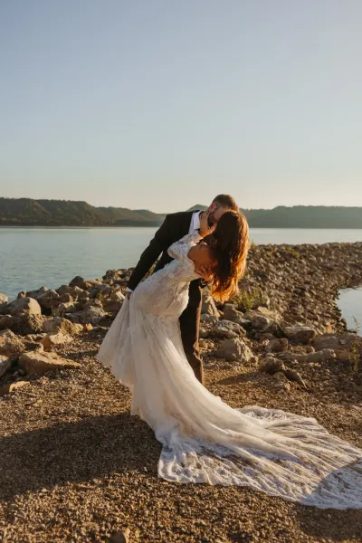 Groom dipping bride for kiss on rocky lakeshore at sunset — Hammond, Minnesota wedding photography by Emma Ziegler, Honey Deww Photography