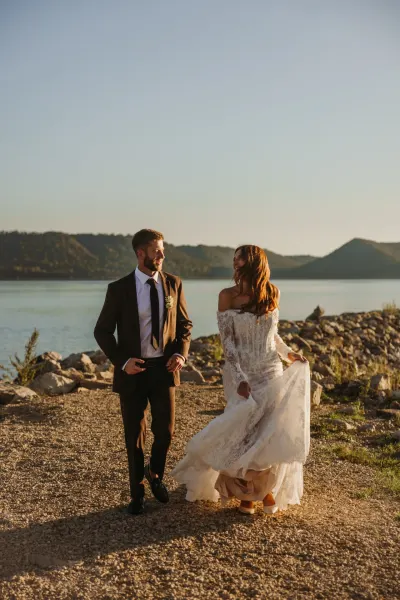 Bride and groom smiling at each other on rocky lakeshore with mountains — Hammond, Minnesota wedding photography by Emma Ziegler, Honey Deww Photography