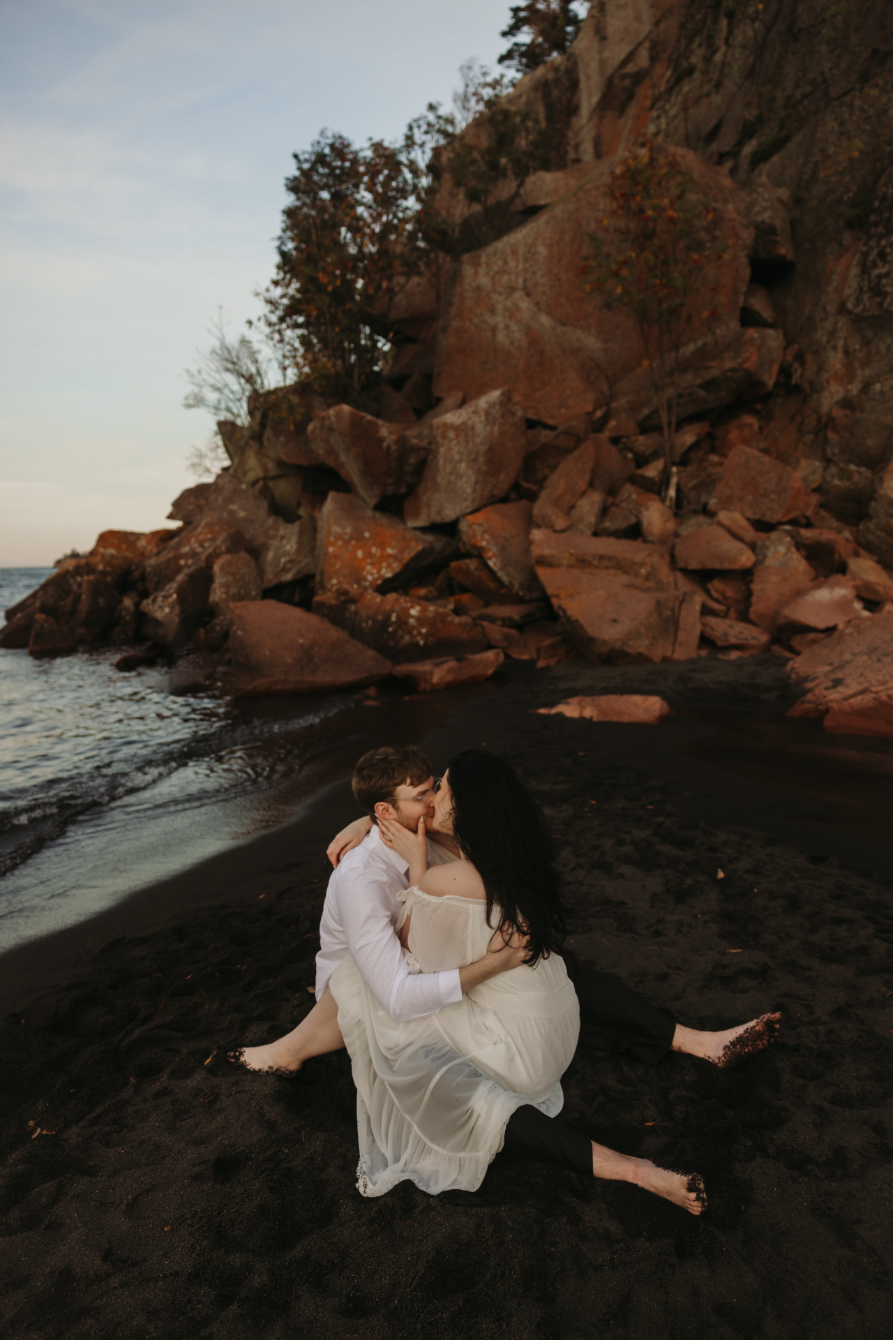 Couple embracing on a rocky beach at sunset