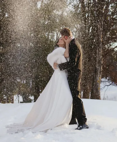 Couple kissing in snow flurry with fur stole and flowing gown — Spring Park, Minnesota wedding photography by Emma Ziegler, Honey Deww Photography