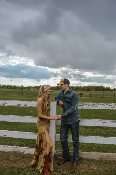Couple holding hands at white fence with stormy sky and farmland — Maple Plain, Minnesota wedding photography by Emma Ziegler, Honey Deww Photography