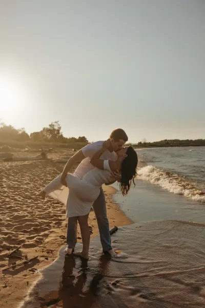 Couple dipping and kissing at shoreline in golden sunset — Maple Plain, Minnesota wedding photography by Emma Ziegler, Honey Deww Photography