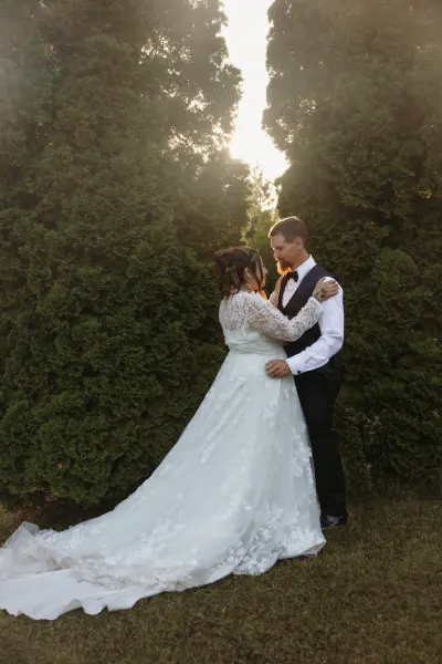 Bride and groom embracing between green arborvitae at sunset — Maple Plain, Minnesota wedding photography by Emma Ziegler, Honey Deww Photography