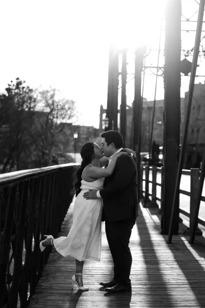 Black and white couple kissing on iron bridge with sunlight streaming through — Deephaven, Minnesota wedding photography by Emma Ziegler, Honey Deww Photography