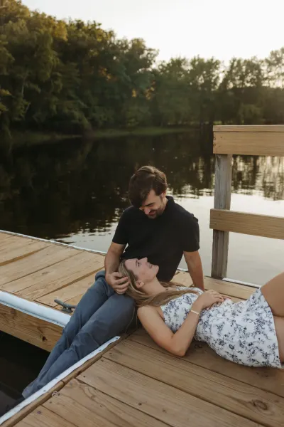 Woman laying in man's lap on wooden dock by lake — Deephaven, Minnesota wedding photography by Emma Ziegler, Honey Deww Photography