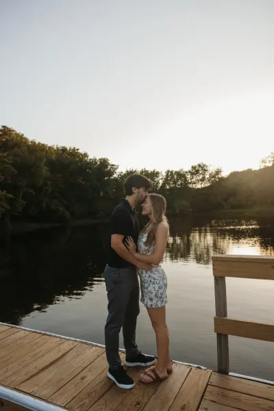 Couple embracing on wooden dock by lake at golden hour — Ellsworth, Minnesota wedding photography by Emma Ziegler, Honey Deww Photography