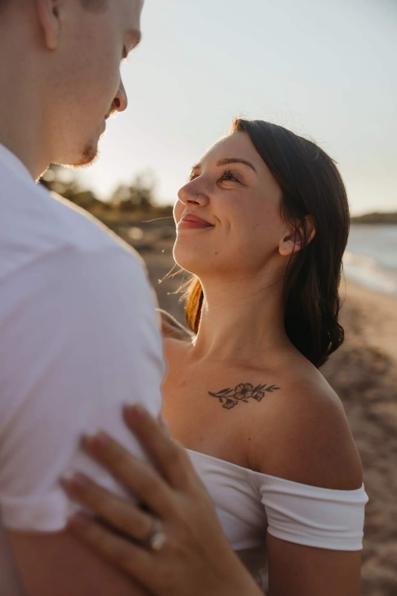 Woman looking up at partner on beach at sunset with flower tattoo — Twin Cities couples & engagement photographer Emma Ziegler, Honeydew Photography (Minneapolis, Minnesota)