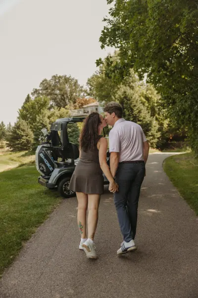 Couple walking and kissing by golf cart on tree-lined path — St. Anthony, Minnesota wedding photography by Emma Ziegler, Honey Deww Photography