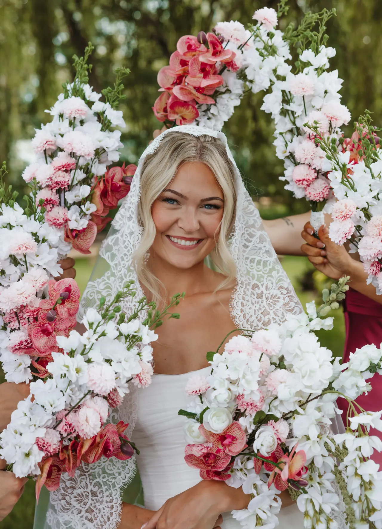 Bride smiling as her bridesmaids hold their bouquets in an arch around her — Minneapolis & Twin Cities wedding photography by Emma Ziegler, Honey Deww Photography (Minnesota)