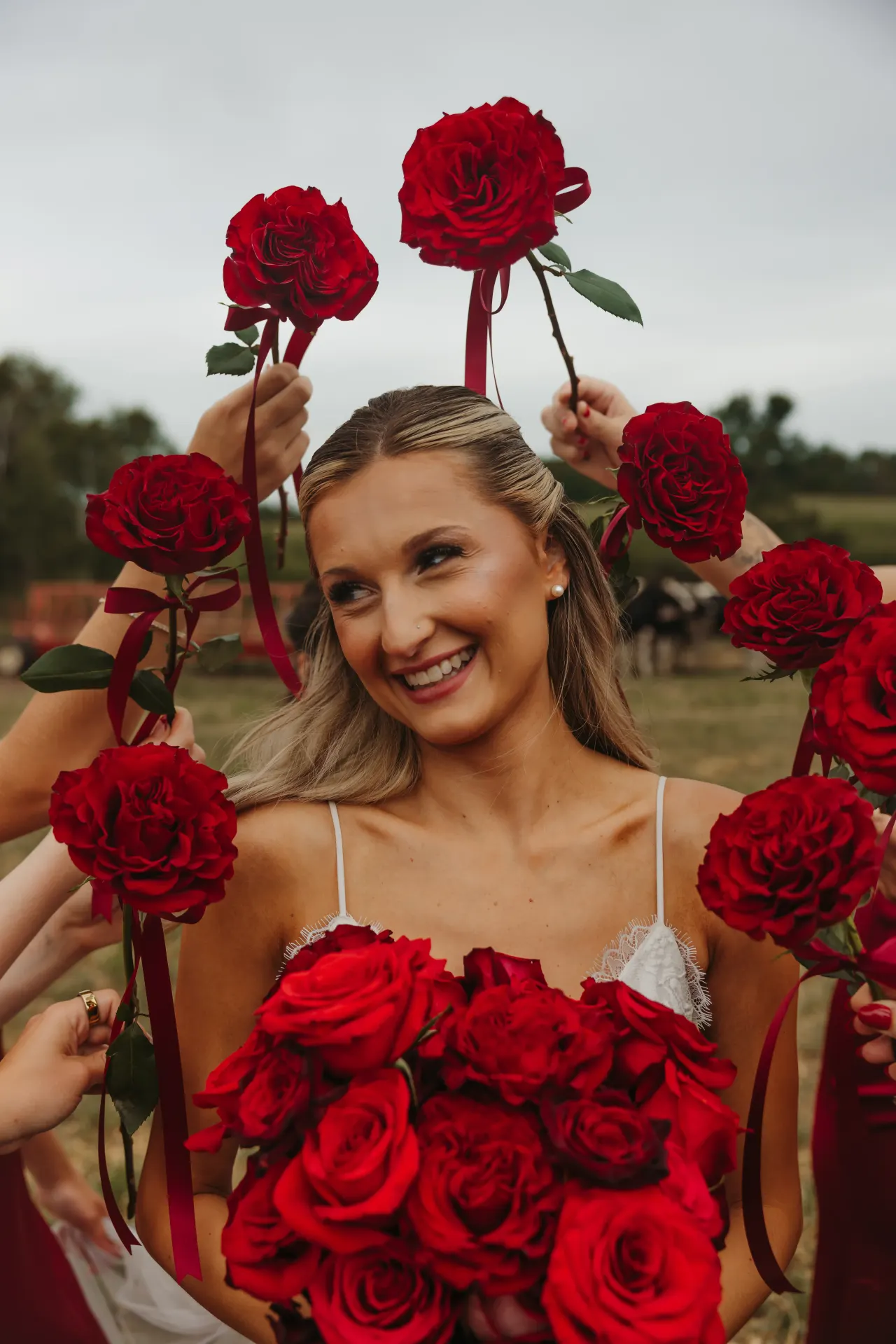 Bride smiling beneath a ring of red roses held up around her — Minneapolis & Twin Cities wedding photography by Emma Ziegler, Honey Deww Photography (Minnesota)