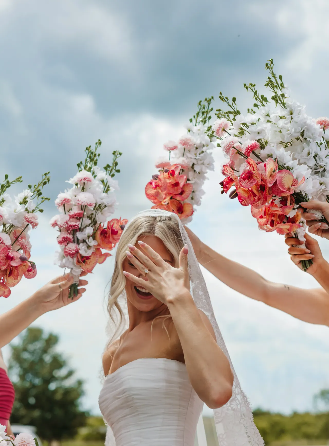 Bride hiding her face and laughing as bouquets are raised around her — Minneapolis & Twin Cities wedding photography by Emma Ziegler, Honey Deww Photography (Minnesota)