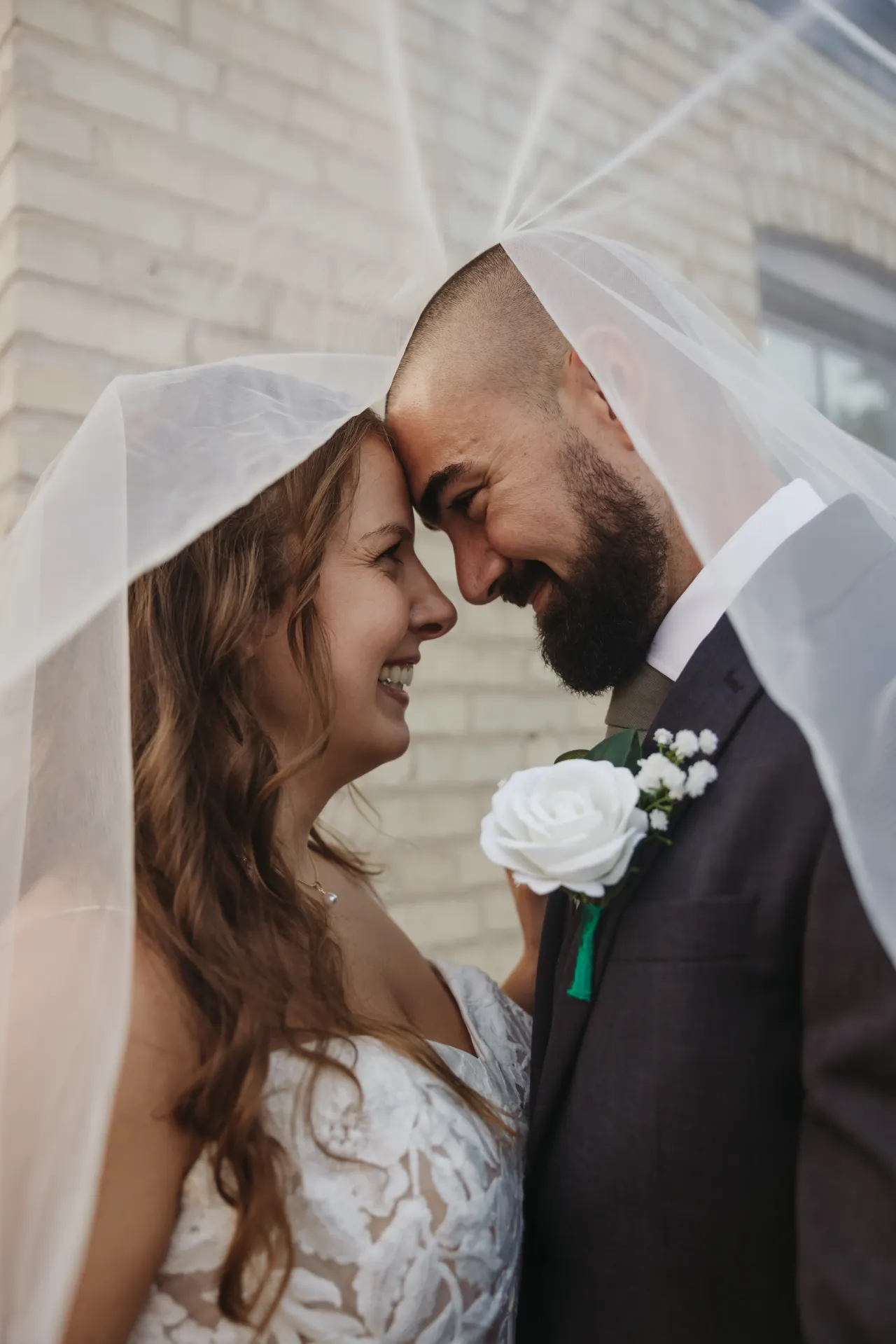Bride and groom forehead to forehead under her veil, a white rose at his lapel — Minneapolis & Twin Cities wedding photography by Emma Ziegler, Honey Deww Photography (Minnesota)