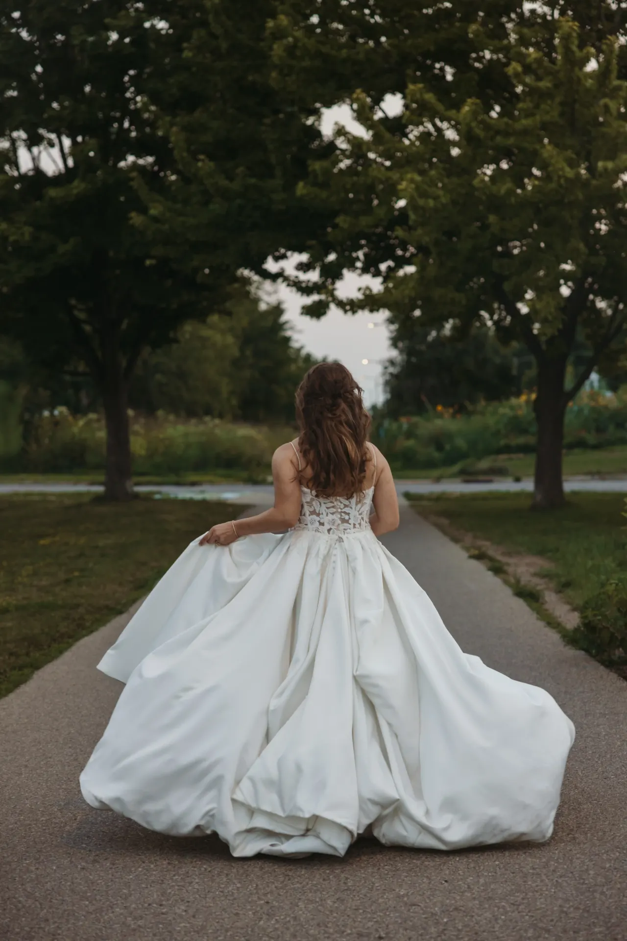 Bride walking away down a tree-lined path, her full skirt spread behind her — Minneapolis & Twin Cities wedding photography by Emma Ziegler, Honey Deww Photography (Minnesota)