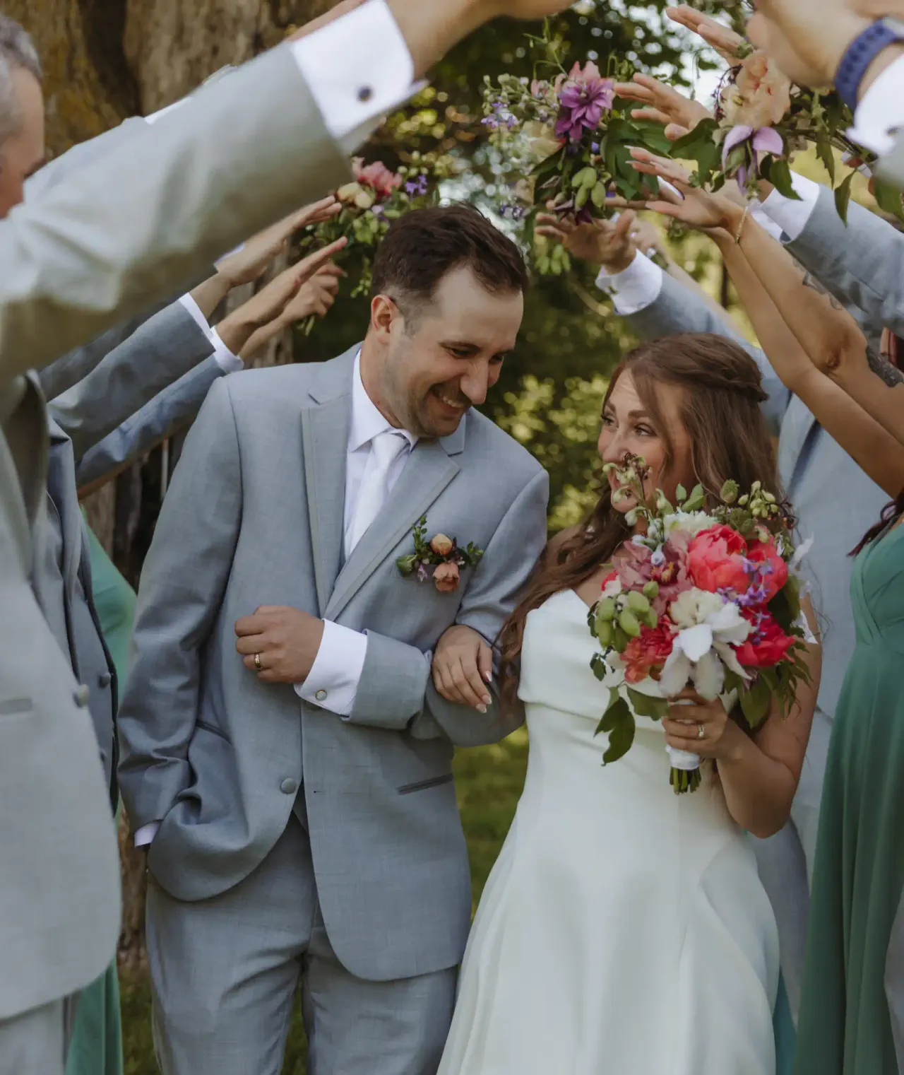 Bride and groom passing beneath their wedding party's raised bouquets — Minneapolis & Twin Cities wedding photography by Emma Ziegler, Honey Deww Photography (Minnesota)