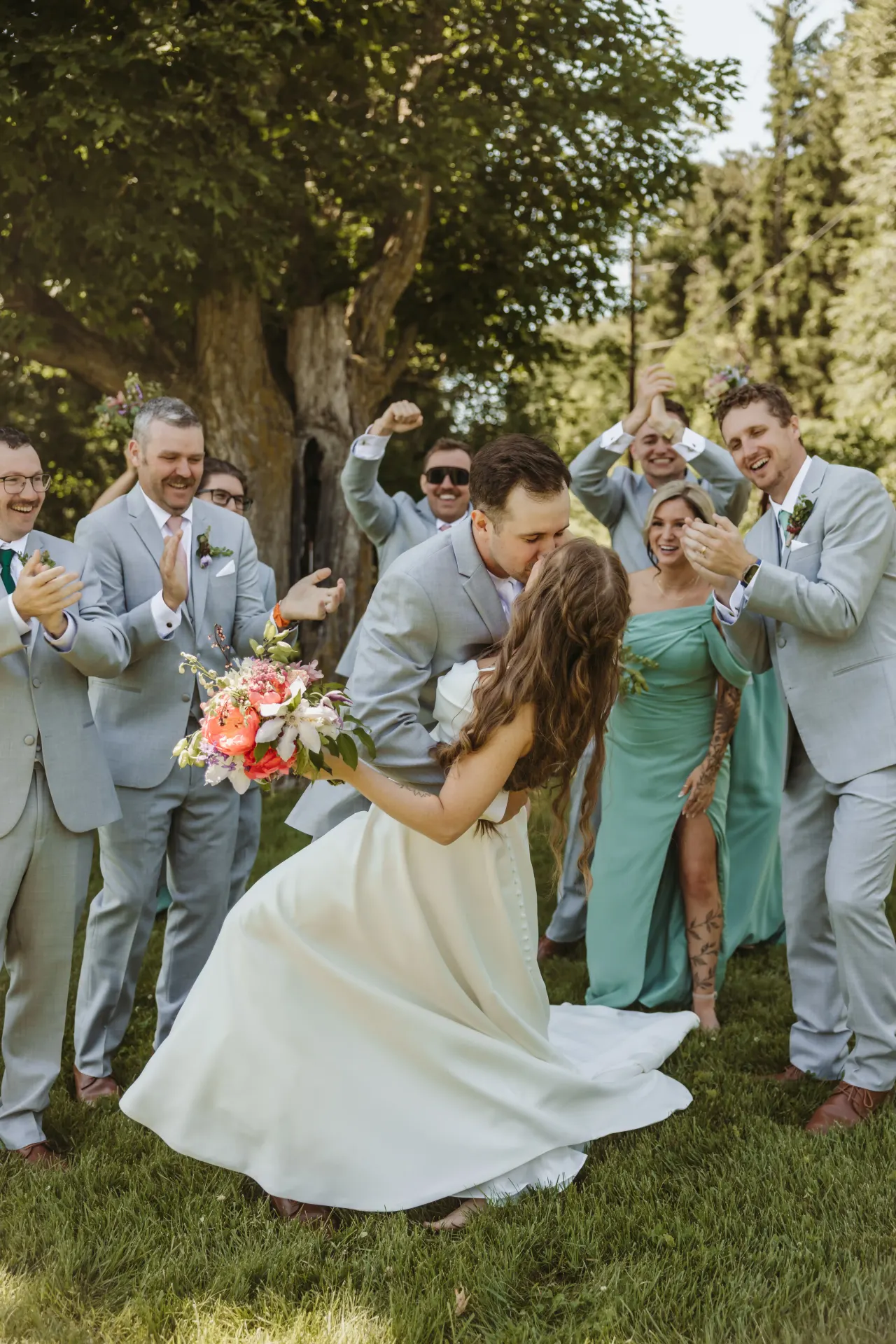 Groom dipping his bride for a kiss as the wedding party cheer around them — Minneapolis & Twin Cities wedding photography by Emma Ziegler, Honey Deww Photography (Minnesota)