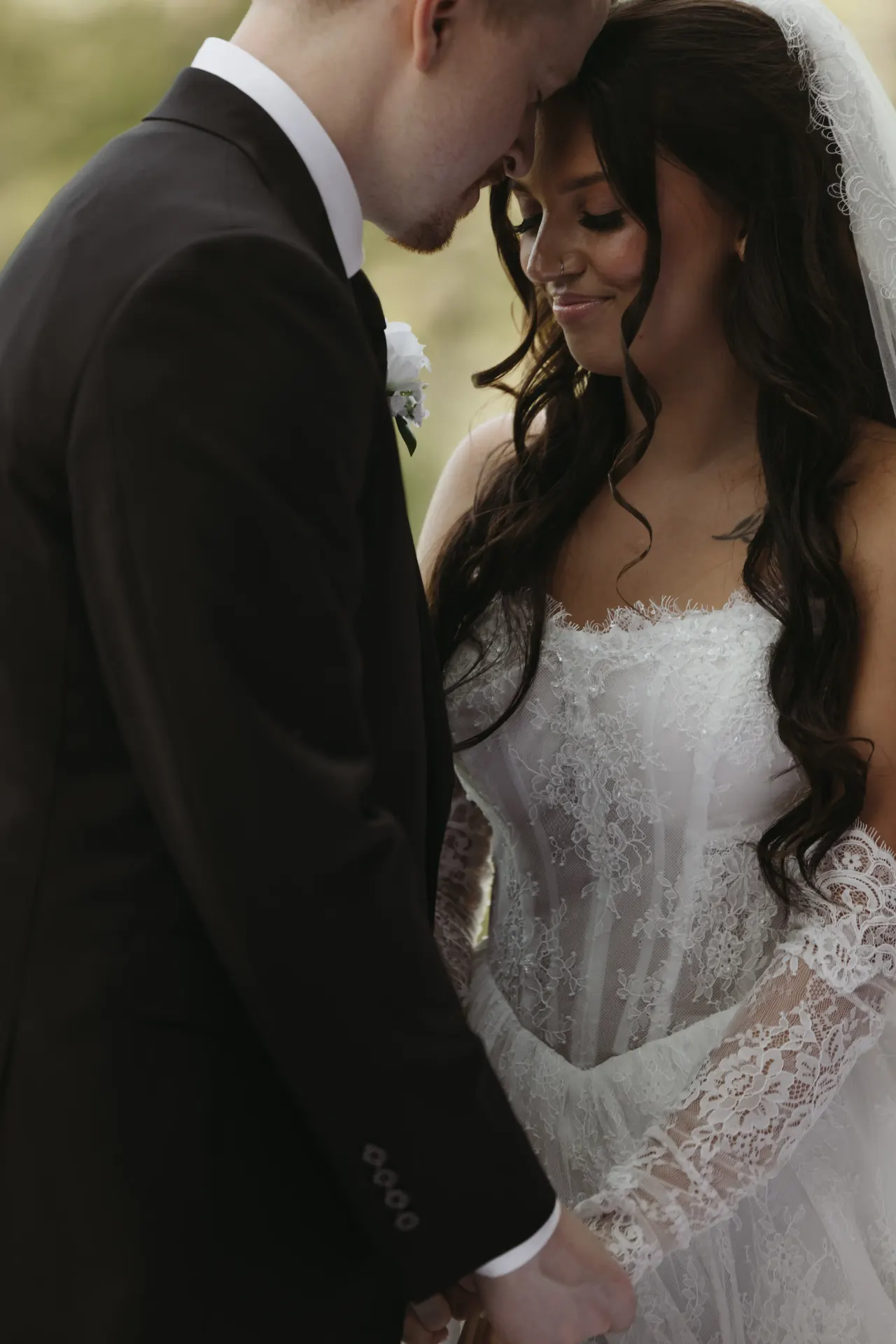 Bride in a lace-sleeved gown resting her forehead against her groom's chest — Minneapolis & Twin Cities wedding photography by Emma Ziegler, Honey Deww Photography (Minnesota)